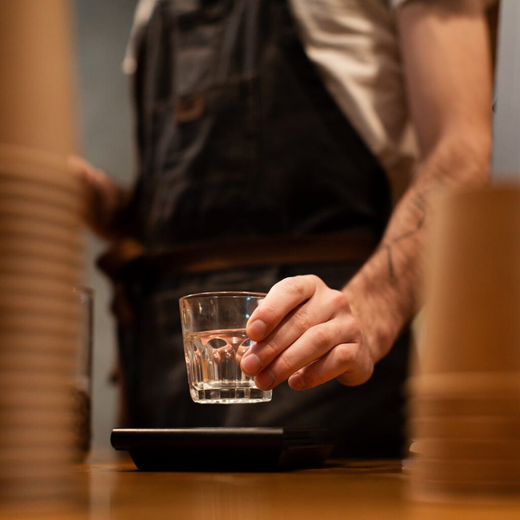 close-up-man-with-apron-holding-clear-glass